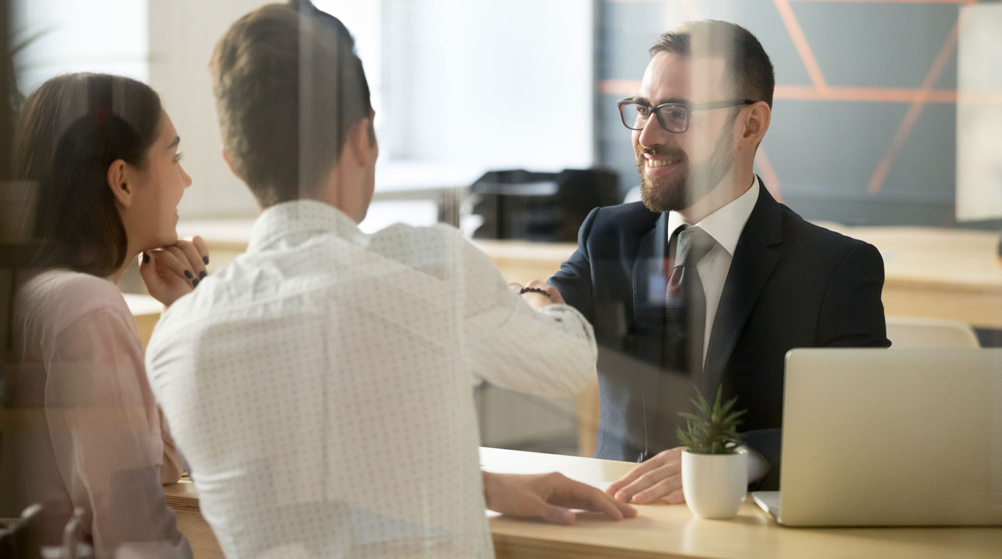 Échange entre un conseiller bancaire et un entrepreneur dans une agence, discussion autour de documents professionnels